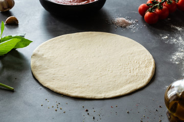 Raw dough, ingredients and spices for pizza Margherita with tomato sauce and Mozzarella cheese on...
