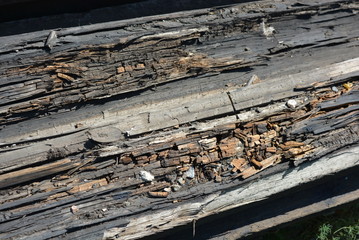 Old black and brown wooden bars from the railway line, broken and cracked by time. Very unique wooden background with unusual color under sunlight.