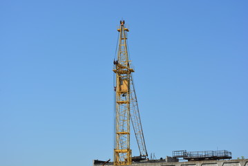 Fototapeta na wymiar Large high-rise metal yellow crane on a background of blue sky.
