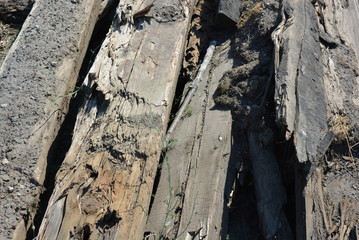 Old black and brown wooden bars from the railway line, broken and cracked by time. Very unique wooden background with unusual color under sunlight.