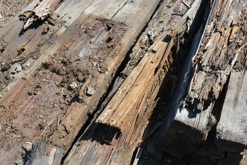 Old black and brown wooden bars from the railway line, broken and cracked by time. Very unique wooden background with unusual color under sunlight.