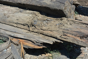 Old black and brown wooden bars from the railway line, broken and cracked by time. Very unique wooden background with unusual color under sunlight.