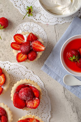 Tartlets with fresh strawberry on light concrete background, top view