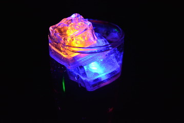 Very beautiful and stunning images of drinks with glowing ice cubes.  Bright colors with bubbles in a glass of champagne.  Promotional image of a relaxing, dear life and a tasty sparkling drink.