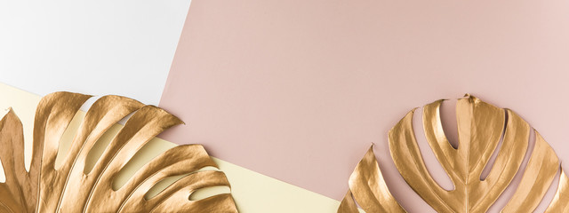 Top view of gold tropical palm Monstera leaf on pink background. Flat lay, view from above. Minimal...