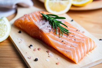 Fresh salmon steak with herbs, lemon and ingredients for cooking in kitchen