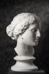 Gypsum copy of ancient statue Venus head on a dark textured background. Plaster sculpture woman face.