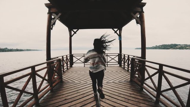 Woman runs towards the end of the wooden pier, Llanquihue lake, Chile. 4k