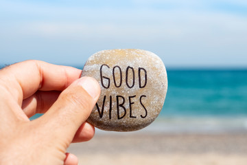 text good vibes in a stone on the beach