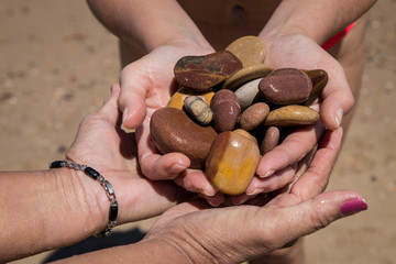 hands grabbing wet beach stones
