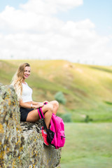 Woman traveler with a view of the mountain landscape. A young tourist woman enjoys the scenery in the mountains. Trekking concept