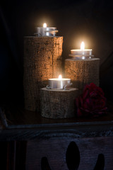 three candles lit in wooden candlesticks