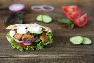 Closeup. Pita - sandwich, sabiche stuffed with chicken, tomatoes, cucumbers, salad on a wooden rustic background decorated with vegetables and pepper. Middle Eastern cuisine. With copy space for text.