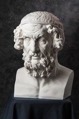 Gypsum copy of ancient statue Homer head on dark textured background. Plaster sculpture man face.