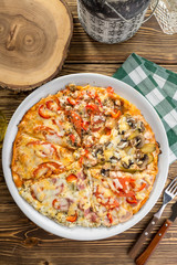 Assorted pizza pieces with ham, mushroom, tomato top view on wooden table