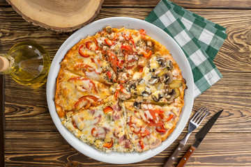 Assorted pizza pieces with ham, mushroom, tomato top view on wooden table