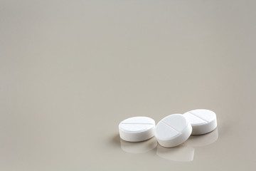 white pills on a beige background with copy space