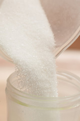 Pouring white sugar into a smaller container for ease of use