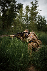 Portrait airsoft soldier with a rifle playing strikeball in outdoor in grass