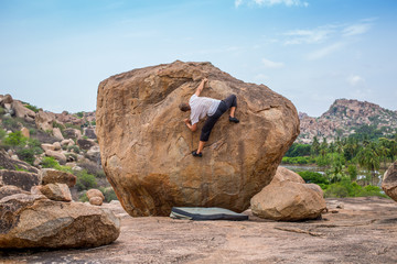 Climbing a boulder in Hampi, India, on a summer afternoon