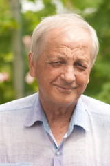 Portrait of a man. Portrait of a smiling elderly man in a light shirt in the summer outside