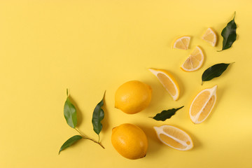lemons and green leaves on a colored background top view.