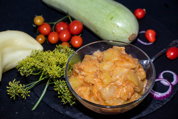 A garden snail, accidentally caught in a hole with cherry tomatoes, crawls along the board and looks for a place to hide. All this is a black background.