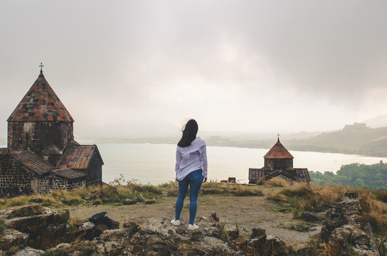 young woman standing near old monastery and looking forward