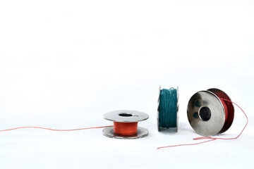 metal spool with colored threads on white background