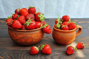 Strawberries in pottery on a wooden table. Side view