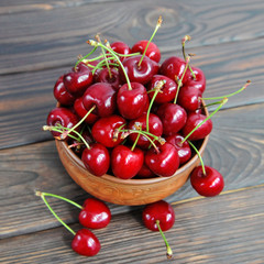 Sweet cherry berries in a clay pot on a wooden table. View from above