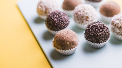 Close-up of chocolate truffles on white tray against yellow backdrop