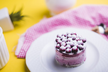 Fresh blueberries on white plate against yellow backdrop