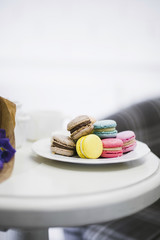 Many colorful macaroons on white ceramics plate over the table