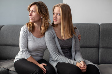 Teenage girl with her mother on a sofa in their living room - having a good parent-child relationship