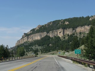 Closer view of a high rocky cliff with a roadside sign at Tensleep Creek in Wyoming.