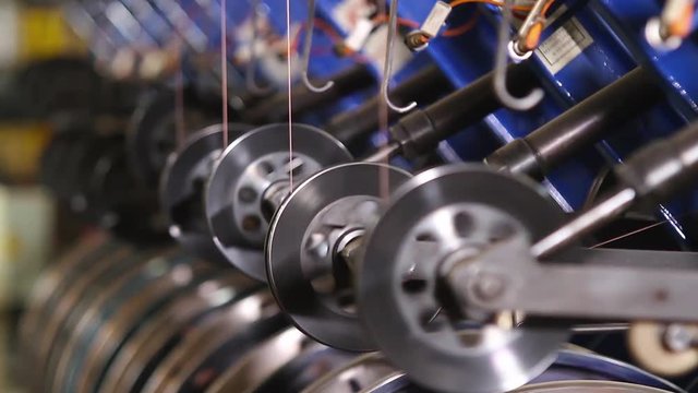 Wire reinforcement of modern tires in a factory. Closeup side view special machine tool reels metal threads for automobile tires at bright ligth. Reinforced steel bronze wire side ring on the tire.
