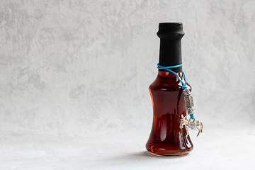 Small bottle of red wine without lable with metal donkey on blue lace on grey cement background...