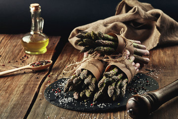 An edible, raw stems of asparagus on a wooden background.