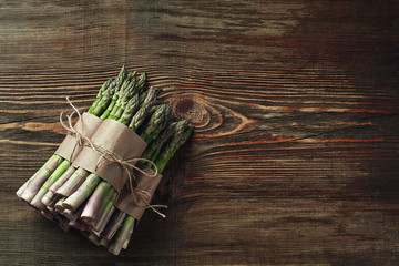 An edible, raw stems of asparagus on a wooden background.