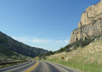 Fototapeta premium Wide view of scenic a road along high rock walls through the Bighorn Mountains in Wyoming.