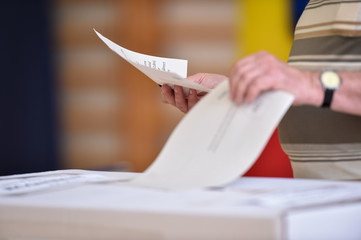 Fototapeta na wymiar Person casting a vote into the ballot box during elections