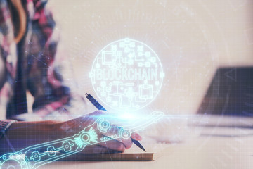Cryptocurrency hologram over woman's hands writing background. Concept of blockchain. Multi exposure