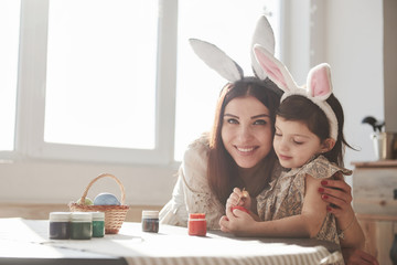 Lovely hugs. Mother and daughter in bunny ears at easter time have some fun in the kitchen at...
