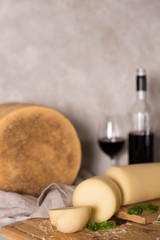 Grated italian parmesan cheese on wooden chopping board with a bottle of wine in the background.