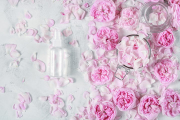 water from roses for beauty and spa care with roses and rose petals on the background