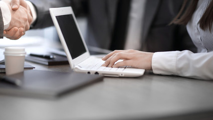 Close up image of business partners handshake over office desk during meeting or negotiation