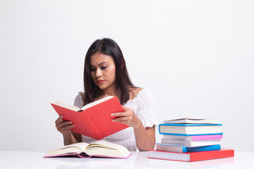 Young Asian woman read a book with books on table.