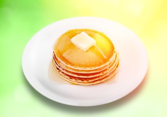 Stack of Small pancakes in syrup on background