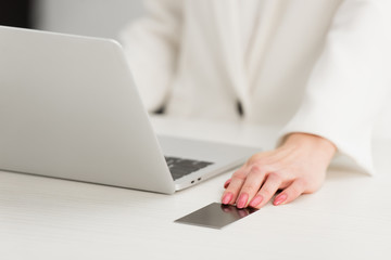 cropped view of businesswoman sitting at workplace and touching empty black business card